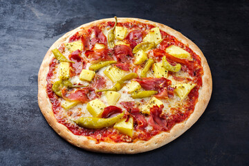 Traditionelle italienische Pizza Hawaii mit Schinken, Ananas und Mozzarella serviert als close-up auf einem alten rustikalen Board mit Textfreiraum 