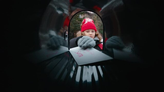 POV Cute little kid boy puts a letter with his Christmas wishes addressed to Santa Claus, Notrh Pole into the mailbox