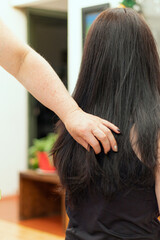 A female stylist touching the freshly styled hair of a long black-haired woman