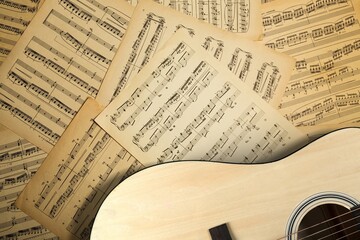 The fretboard of an old vintage acoustic guitar with strings next to sheets of music. A musical instrument. - obrazy, fototapety, plakaty