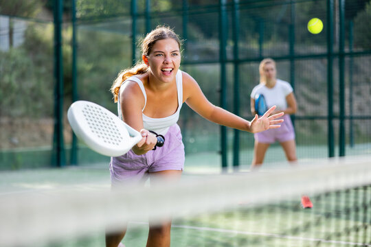 Emotional Young Woman Tennis Player With A Padel Racket Training On An Outdoor Court, Hitting The Ball