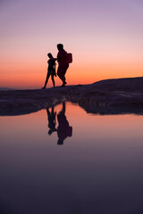 Fototapeta premium A fun family by the lake at sunset, reflection and silhouette, golden hours, Pamukkale travertines - Denizli