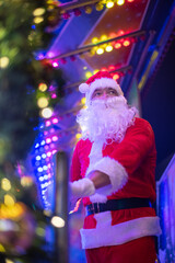 Portrait von einem verkleideten Weihnachtsmann, der auf einem Weihnachtsmarkt von Bokeh von bunten...