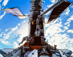 Astronauts servicing the Hubble telescope in space. Planet earth seen in the background. Digitally enhanced. Elements of this image furnished by NASA.