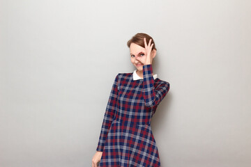 Portrait of happy young woman showing okay gesture near her eye