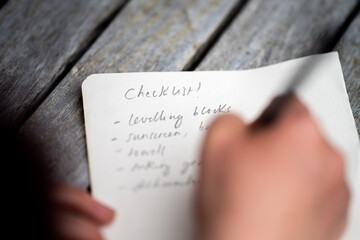 gril writing a camping list in a piece of paper. writing a check list with a pencil