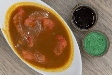 Overhead view of spicy bowl of traditional Indial meal, fish curry served with humus dipping sauce...