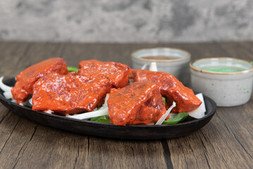Generous portions of lamb boti kabab meat served over a bed of onions and humus dipping sauce for a traditional Indian meal