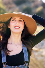 Country girl holding straw hat in the breeze