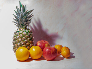 Tropical fruits on a pink background. Pineapple, apples, oranges, tangerines.
