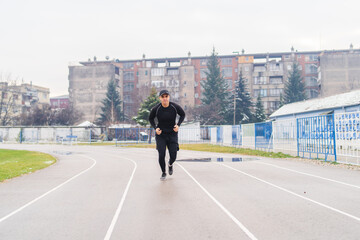 A young man training running stretching jumping a rope on the stadium early in the cold morning 