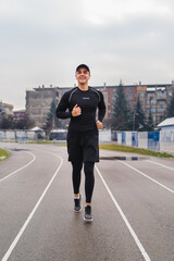 Fototapeta na wymiar A young man training running stretching jumping a rope on the stadium early in the cold morning 