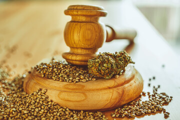 Legality of Medical Cannabis and Seeds, legal and illegal Cannabis, Seeds on the World - Wooden judge hammer and sound block with seeds and flower of marijuana CBD on the pinewood table background.