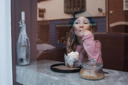young girl sat in a cafe eating cake and drinking hot chocolate