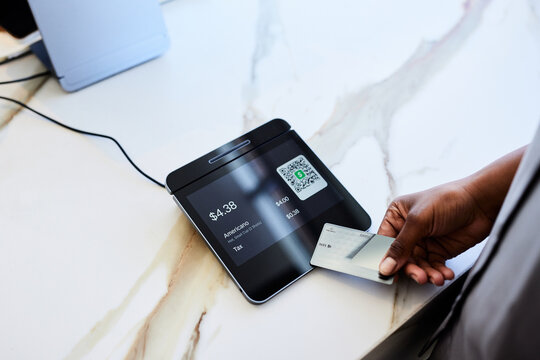 Hand of female customer paying on POS system in coffee shop