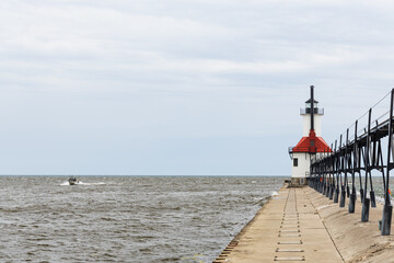Fototapeta na wymiar Boat on Lake Michigan coming into the channel at St. Joseph North Pier Lighthouse on Lake Michigan
