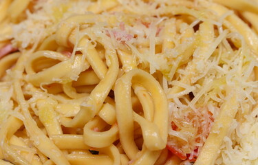 tagliatelle with grated cheese and a few pieces of tomato. closeup on italian food. food made from pasta.