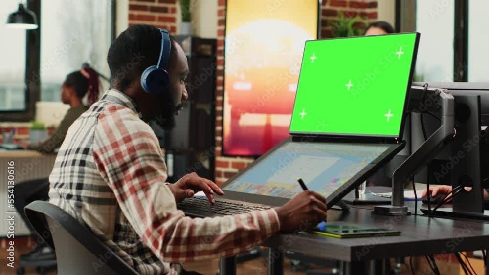 Poster young content creator using greenscreen background on computer, retouching photos with editing softw