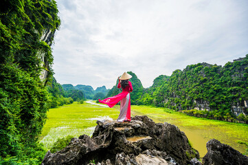 Asian women wearing conical hats and traditional Vietnamese cultural costumes in Tam Coc, Vietnam.