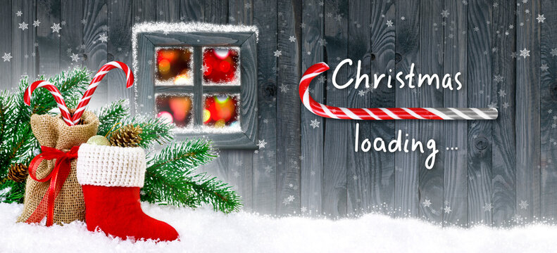 Christmas loading bar in candy cane form showing progress load on wooden boards, Santa's boot and bag with gifts, fir tree branch and cones on house wall background and glowing cozy lights in window.