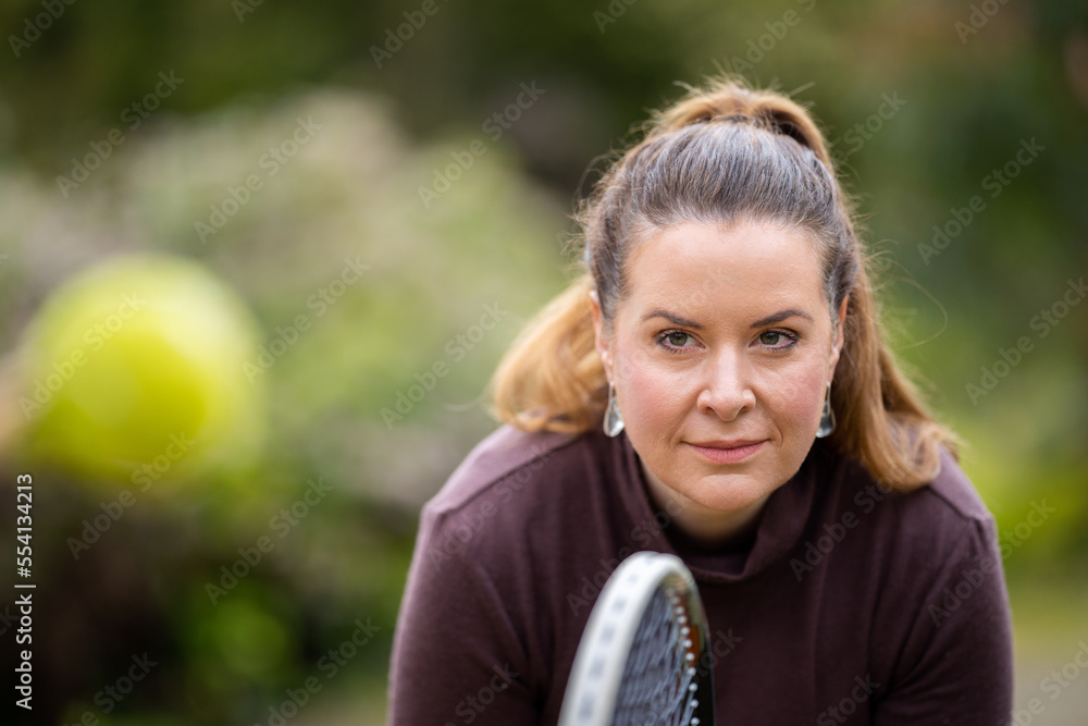 Wall mural female tennis player practicing forehands and hitting tennis balls on a grass court in england