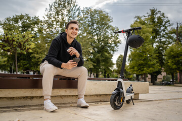 one man sitting on the bench in town with electric kick scooter