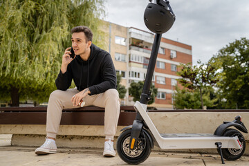 one man sitting on the bench in town with electric kick scooter