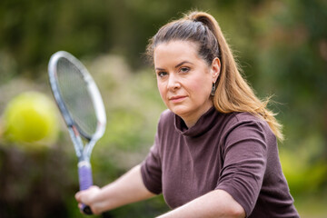female tennis player practicing forehands and hitting tennis balls on a grass court in england - obrazy, fototapety, plakaty
