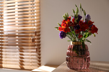 Vase with beautiful flowers on wooden table in room, space for text