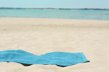 Obraz premium Blue towel on sandy beach near sea, space for text
