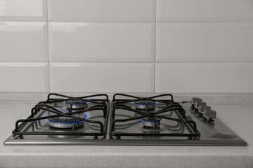 Gas cooktop with burning blue flames in kitchen