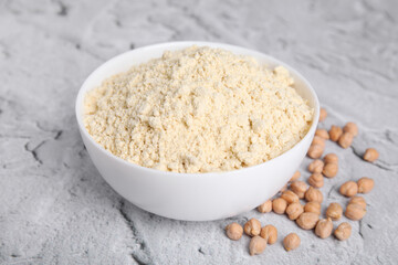 Chickpea flour in bowl and seeds on light grey textured table