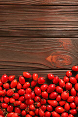 Fresh ripe rosehip berries on wooden table, flat lay. Space for text