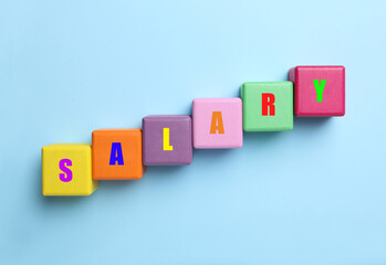 Word Salary made with colorful cubes on light blue background, flat lay