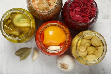 Many jars with different preserved products on white table, flat lay