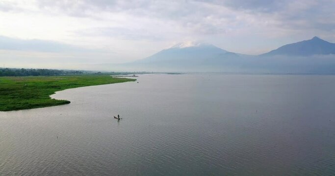 The fishing boat is on the huge lake looking for fish with mountain background - Rawa Pening Lake, Indonesia