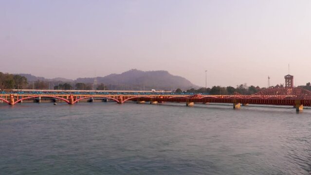 isolated iron bridge many over ganges river with wide view of city at riverbank at evening aerial video is taken at har ki pauri haridwar uttrakhand india on Mar 15 2022.