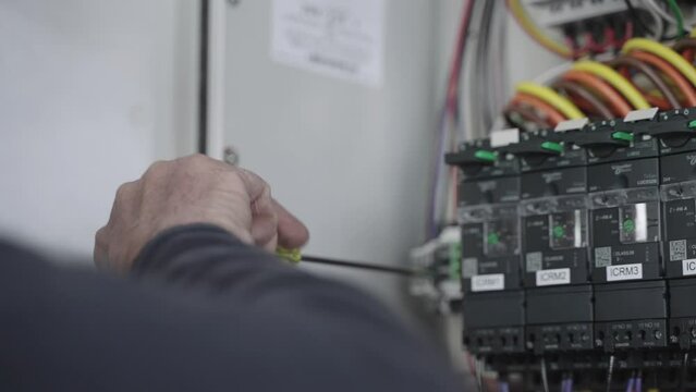 Electrical mechanical worker using screwdriver to fix distribution electric box, slow motion