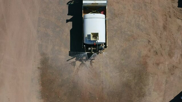 Aerial Drone Top View Of Water Truck Spraying Water To Suppress Dust On Barren Construction Site