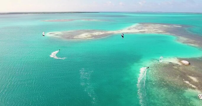 Two men kitesurfing near House typical of primitive civilizations built on wooden stakes, inside caribbean sea
