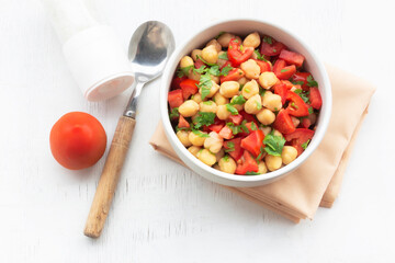 Healthy food chickpeas salad add tomato coriander in white bowl on wood background.