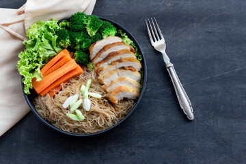 Healthy food fried rice noodle has chicken and carrot broccoli in black bowl on wood background.