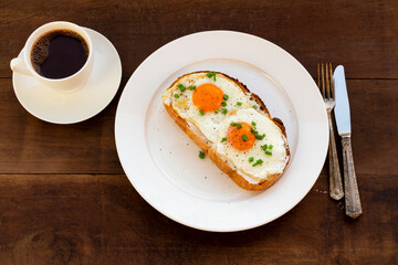 Breakfast food fried egg on toast has coffee on wood table.
