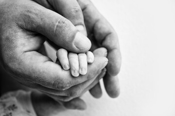 The hand of sleeping newborn in the hand of parents, mother and father close-up.