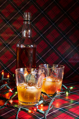 Two beverages and an alcohol bottle with Christmas lights