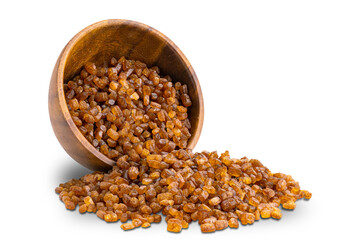Side view of dry sweet organic crystal caramel flowing out of wooden bowl isolated on white background with clipping path.
