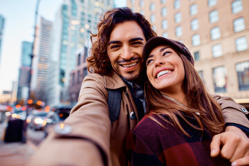Young happy couple having fun while taking selfie in city.