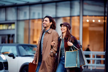 Happy couple crossing street while shopping in city.