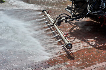 A special machine washes city paths and roads with water