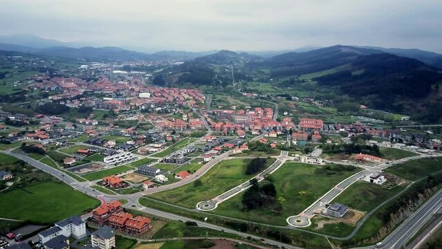 Sopelana Bilbao aerial drone shot over the leafy mountains of Vasque Country with floating dawn clouds on a clear sunny day blue skies drone show majesty of mountain the small houses of the villagers